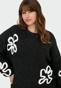 Zwarte gebreide trui met witte geborduurde bloemmotieven aan de voorkant, met een ronde halslijn en een losse pasvorm.