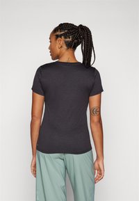 Tricou scurt de culoare gri închis, cu guler rotund, design ajustat și textură netedă, asortat cu pantaloni verzi deschis.
