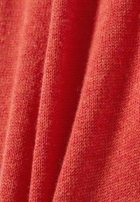 Rode gebreide stof met een zachte, gestructureerde oppervlakte en subtiele kleurvariaties. Het materiaal ziet er warm en iets fuzzy uit.