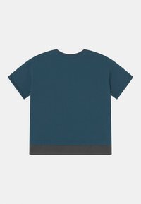 Camiseta de algodão em tom teal, com mangas curtas, decote redondo e bainha em cinza escuro contrastante na parte inferior. Textura suave, design casual.