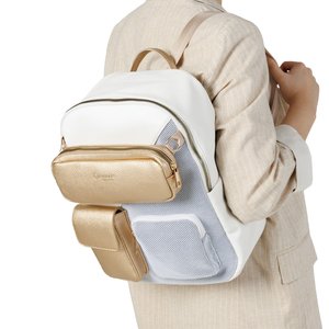 Persona che indossa un abito beige con uno zaino bianco con tasche frontali e cerniere dorate e bianche.