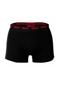 Black boxer shorts with a smooth texture, featuring a contrasting red elastic waistband with repeated "HUGO" branding.