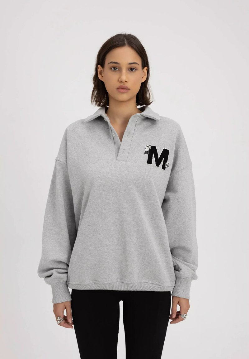 Szary sweter z kapturem i kołnierzykiem, z haftowanym czarnym logo "M" na lewej piersi oraz długimi, luźnymi rękawami.