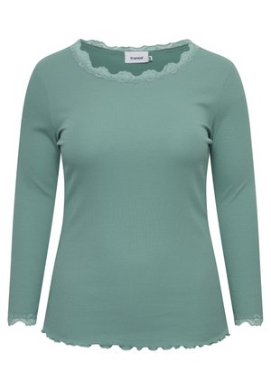 Mintgrøn langærmet top lavet af ribbet stof, med en bølget blondekant ved halsudskæringen og ærmekanterne, samt en afrundet bund