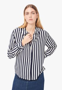 Camicia a righe blu navy e bianca con maniche lunghe, colletto, patta con bottoni e una vestibilità comoda. Tessuto morbido con una trama liscia.
