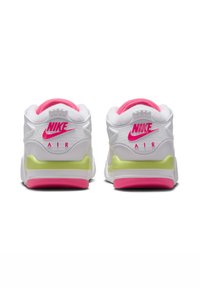 Nike Air-sneakers har en övervägande vit design med klara rosa accenter, grön mellansula, vadderad krage och en distinkt logotyp på hälen.