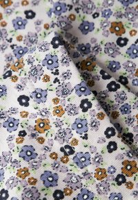 Kwiatowa tkanina o jasnobeżowym tle, z drobnymi niebieskimi, fioletowymi i brązowymi kwiatami, teksturowanym splotem oraz subtelnymi zielonymi akcentami.