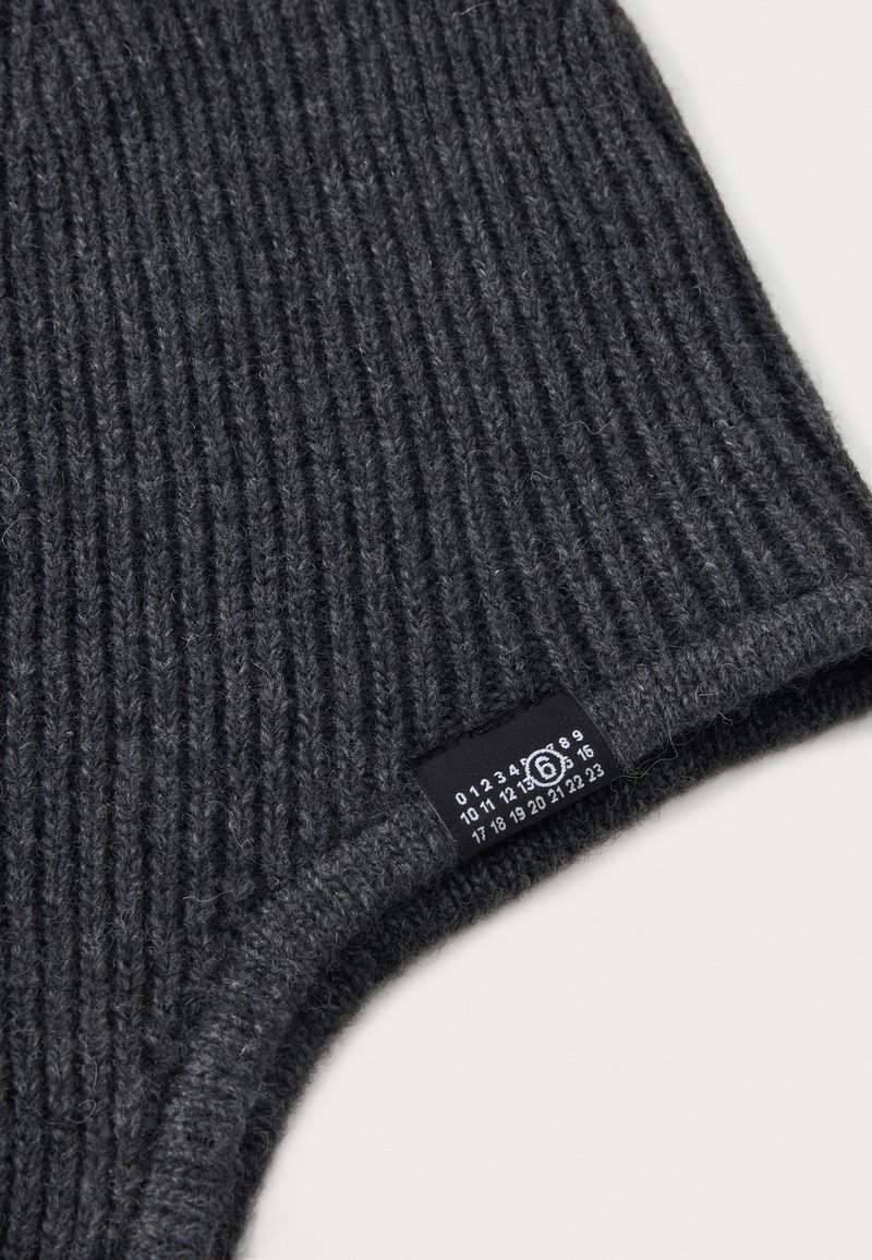 Tissu tricoté côtelé gris foncé avec une étiquette rectangulaire noire comportant des chiffres blancs et un numéro 6 entouré près du bord sur une surface claire.