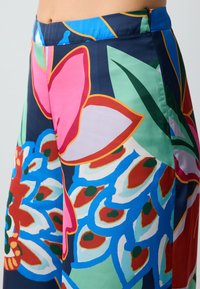 Kleurige broek met een bloemen- en bladpatroon in roze, groen, blauw en rood. Gemaakt van een soepele stof met een aansluitende taille.