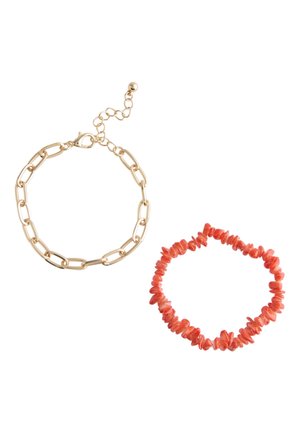 Gold chain bracelet with large links and lobster clasp next to an elastic bracelet made of irregular coral-colored beads.