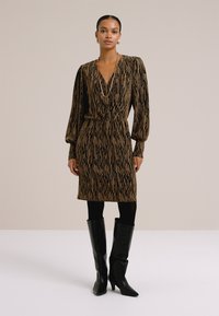 Rjava in črna obleka s potiskom, dolgimi rokavi, ožjim pasom in globokim V-izrezom; v kombinaciji z črnimi škornji do kolen.