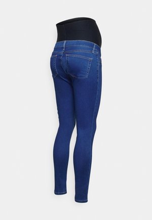 Hoog getailleerde blauwe zwangerschaps-skinny-jeans met een rekbare zwarte tailleband die bedoeld is om de zwangere buik te ondersteunen, gezien van achteren.