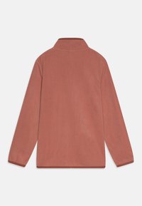 Fleece genser i myk rosafarge med høy krage, lange ermer og rundet kant. Jevn tekstur med kontrasterende kant langs kantene.