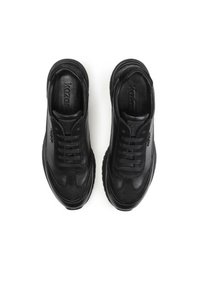 Zapatillas de cuero negro con punta redondeada, diseño de cordones y acentos texturizados. La suela presenta un patrón de banda de rodadura deportivo para mayor tracción.