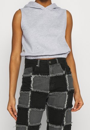 Bezrękawnik w jasnoszarym kolorze z krótkim krojem, zestawiony z wysokim stanem czarnych i szarych dżinsów patchworkowych z postrzępionymi krawędziami.