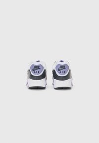 Nike Air sneakers with a predominantly white upper, purple accents, and a black heel. Durable material, textured surface, and branding on the back.