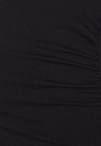 Top preto ajustado feito de tecido elástico, com textura franzida de um lado, criando um subtil efeito de onda ao longo da costura.