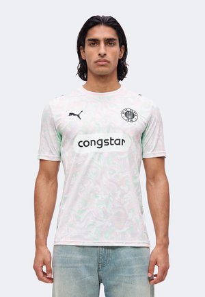 Mann mit dunklen Haaren, der ein helles marmoriertes Fußballtrikot mit Puma-Logo, FC St. Pauli-Wappen und "congstar"-Sponsor trägt, vor einfachem Hintergrund steht.