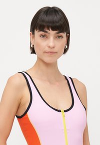 Costume da bagno intero rosa e arancione con rifiniture nere e una zip gialla. Presenta un design aderente e una texture liscia e elastica.