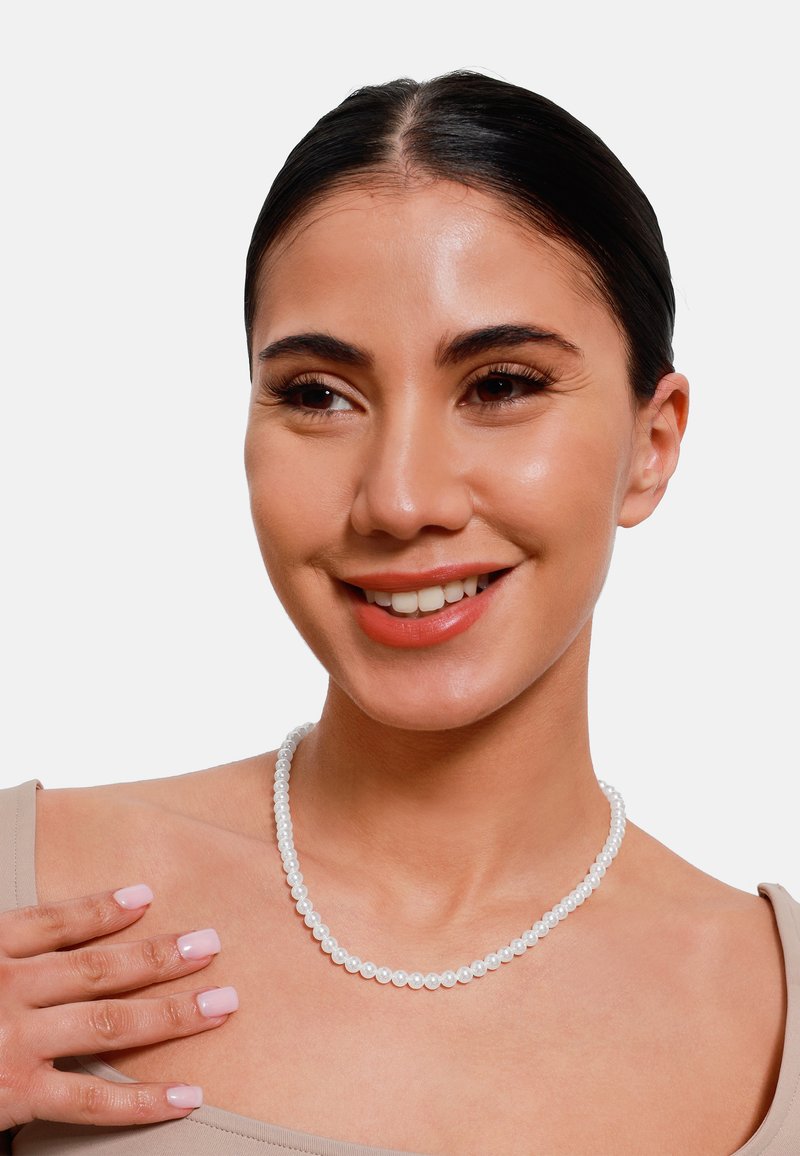 Witte parelketting met gelijkmatig gevormde parels, een soepele textuur en een klassiek ontwerp, gedragen tegen een simpele, neutrale achtergrond.