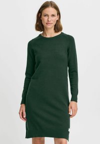 Sinna tumeroheline kudum dresses pika varrukaga, ümmarguse kaelusega ja küljetükkidega. Omab siledat tekstuuri ja väikest logo sildi hemus.