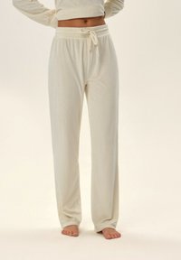 Kremowe, prążkowane spodnie dresowe z elastycznym pasem i sznurkiem. Charakteryzują się luźnym krojem, prostymi nogawkami i miękką teksturą.