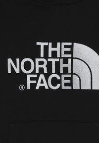 Černá mikina s velkým vyšitým šedým logem "THE NORTH FACE" a charakteristickým zakřiveným designovým prvkem.