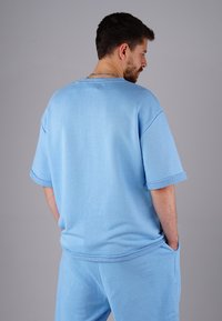Light blue short-sleeve t-shirt with a relaxed fit, made of soft material, featuring a round neckline and visible seam details.