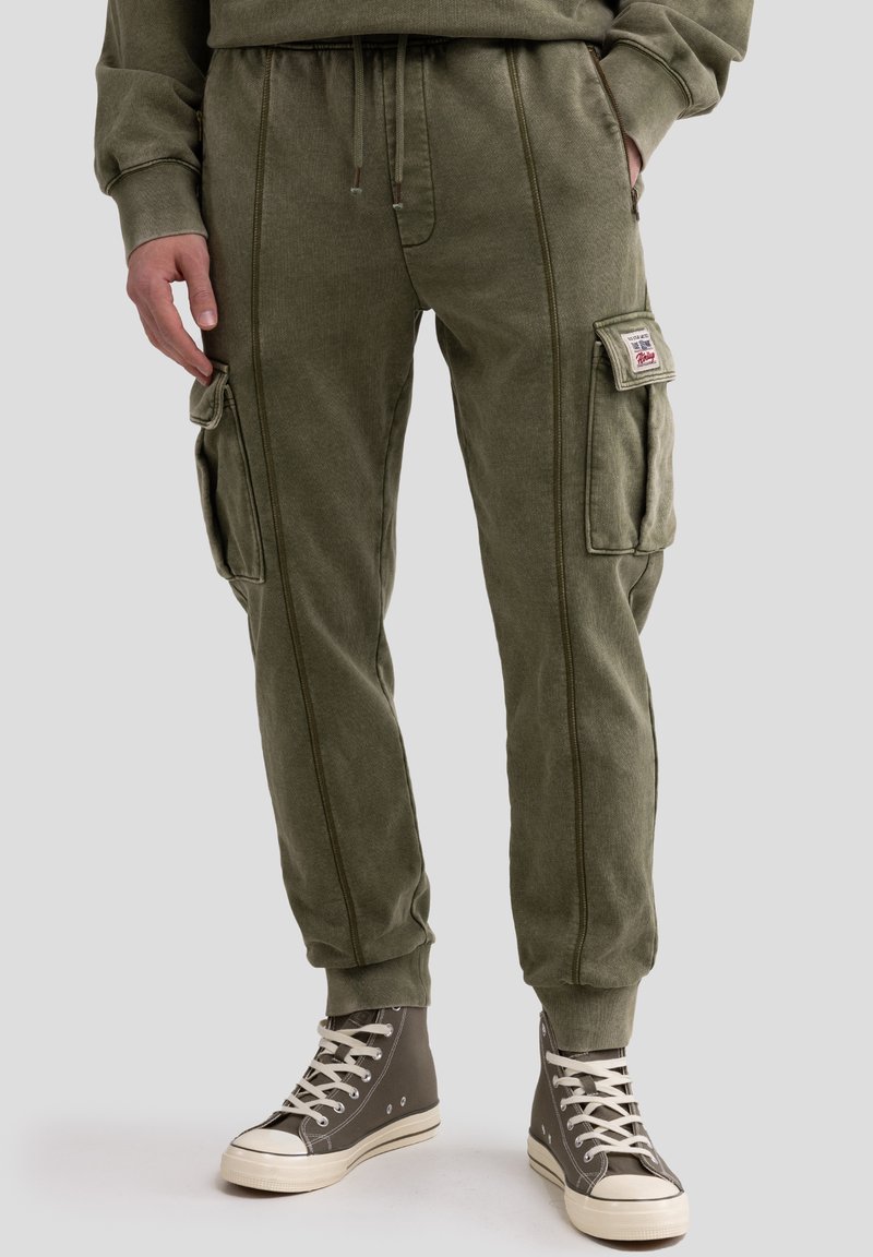 Pantaloni cargo verde oliva in morbido cotone misto, con tasche laterali, polsini elasticizzati e cuciture visibili per un tocco di dettaglio.