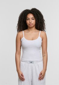 Gray ribbed tank top with thin straps and a round neckline, worn with light gray sweatpants featuring an elastic waistband and logo.