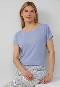 Lichtpaarse korte mouwen top met een ronde halslijn. Zachte, gladde stoftextuur. Gecombineerd met gemusterde, meerkleurige chevron broek.