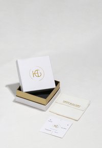 Fehér doboz arany díszítéssel, "H&G" logóval. Fekete belső, textil tasak és termékinformációs kártya található benne.