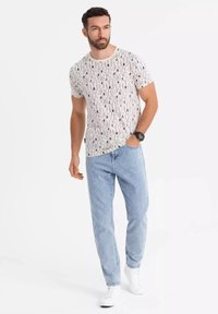 Hvid t-shirt med sort, vertikalt tekstmønster; lyseblå denim jeans; hvide sneakers; afslappet pasform, korte ærmer, rund hals design.