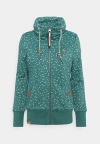 Felpa verde con un motivo floreale, colletto alto, chiusura con zip, coulisse regolabili con dettagli in legno e tasche laterali con zip.