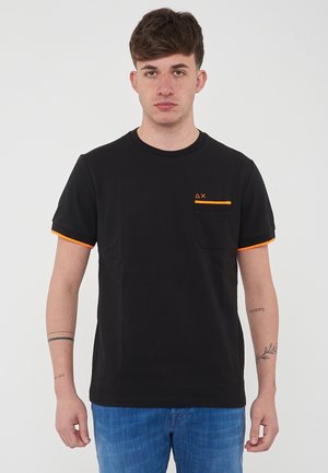 T-shirt nera in cotone a maniche corte con dettagli su tasca arancione, cinturini arancioni a contrasto sulle maniche e design a collo rotondo.