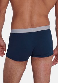 Boxer di colore blu navy con un cinturino grigio chiaro, caratterizzati da una texture liscia, design aderente e un taglio all'altezza della coscia.