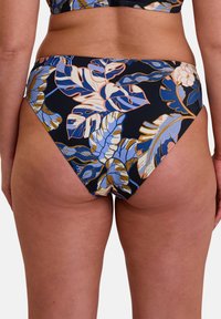 Bas de bikini floral en bleu marine foncé, ornée de motifs de feuilles tropicales bleues et beiges. Couvrance moyenne avec une texture de tissu lisse.