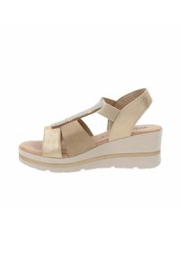 Sandali con zeppa beige dal finish liscio, caratterizzati da una cinghia scintillante e una banda alla caviglia regolabile, progettati per comfort e stabilità.