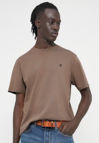 Καφέ βαμβακερό t-shirt με κοντά μανίκια, στρογγυλή λαιμόκοψη και μικρό μαύρο λογότυπο "II" στο αριστερό στήθος. Κανονική εφαρμογή και ομαλή υφή.