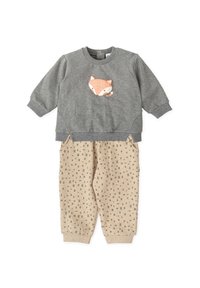 Sudadera gris con un gráfico de un zorro, combinada con pantalones beige de estampado que presentan pequeños cuadrados. Tejido suave, estilo casual.