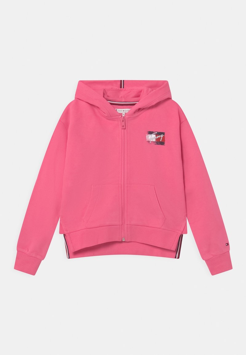 Haut zippé rose en coton doux. Présente un patch logo graphique sur la poitrine, des poches kangourou et des poignets côtelés.