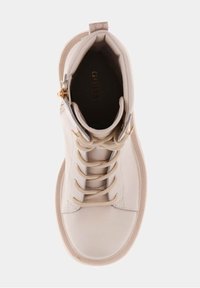 Zapatilla alta blanca con un exterior de cuero suave, cordones crema, detalles en dorado y un cuello acolchado. Presenta una punta redonda y una suela texturizada.
