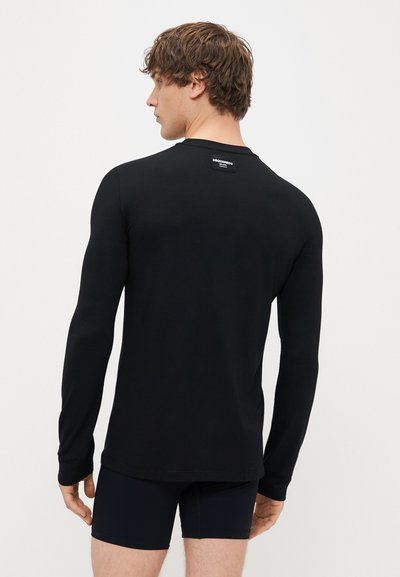 Juodas ilgomis rankovėmis marškinėliai, pagaminti iš minkštos audinio, su apvaliu iškirpimu ir etikete gale. Prigludęs siluetas, su siaurėjusiomis rankovėmis.