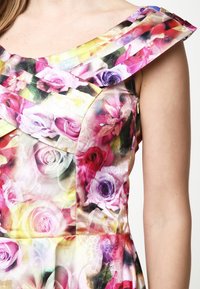 Blumenkleid mit einem bunten Rosenmuster auf einem leichten Stoff; schulterfreier, geraffter Ausschnitt mit glatter Textur und dezentem Glanz.