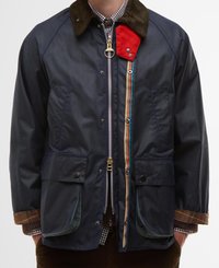 Casaco impermeável azul-marinho com colarinho de corduroy, detalhes em vermelho, fita de zíper multicolorida, dois bolsos frontais e um logótipo discreto no bolso.