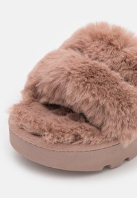 Chausson en peluche marron ouvert à l'avant, avec de larges sangles en fausse fourrure douce et une semelle texturée et coussinée pour un confort intérieur.