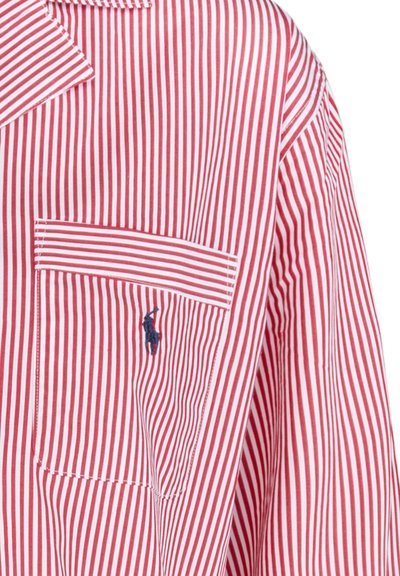 Červenobíle pruhované tričko s kapsou na hrudi a vyšívaným logem. Vyrobeno z látky s hladkým povrchem. Klasický límec.