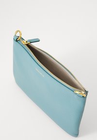 Šviesiai mėlyna odinė kišenė su auksine užtrauktuku, auksiniu žiedu, užsegimui ir šviesiai ruda vidine puse, paženklinta mažomis auksinėmis "Coccinelle" raidėmis.