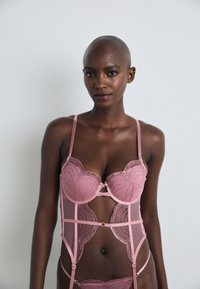 Pink lace lingerie set featuring a structured bra with scalloped edges, mesh panels, decorative stitching, and adjustable straps.