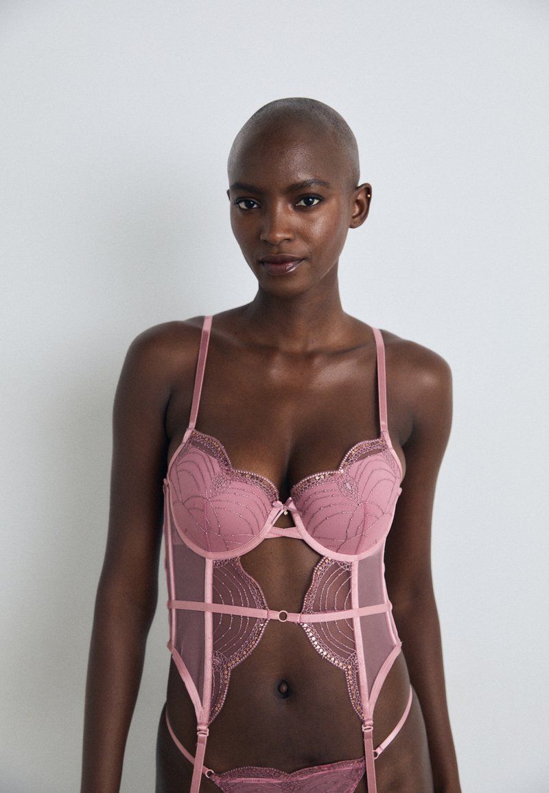 Pink lace lingerie set featuring a structured bra with scalloped edges, mesh panels, decorative stitching, and adjustable straps.